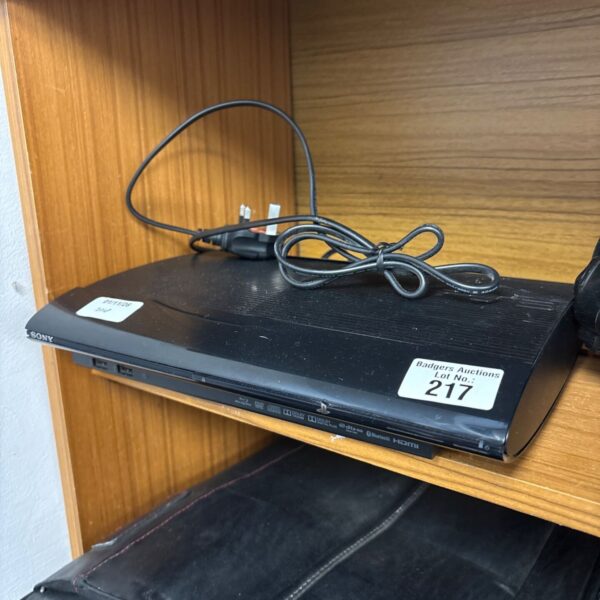 Black Sony PlayStation 3 Super Slim console with mains lead on wooden shelf