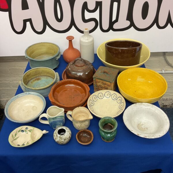 Collection of glazed studio pottery bowls, dishes and pots on a blue cloth