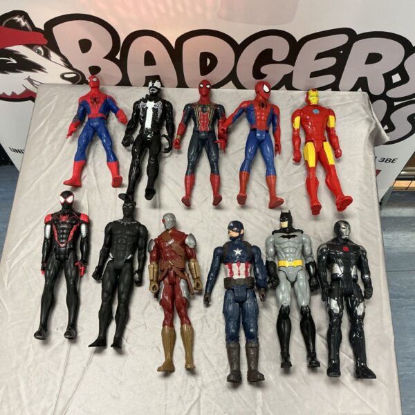 Eleven superhero action figures including Spider-Man, Iron Man and Batman on a light fabric surface