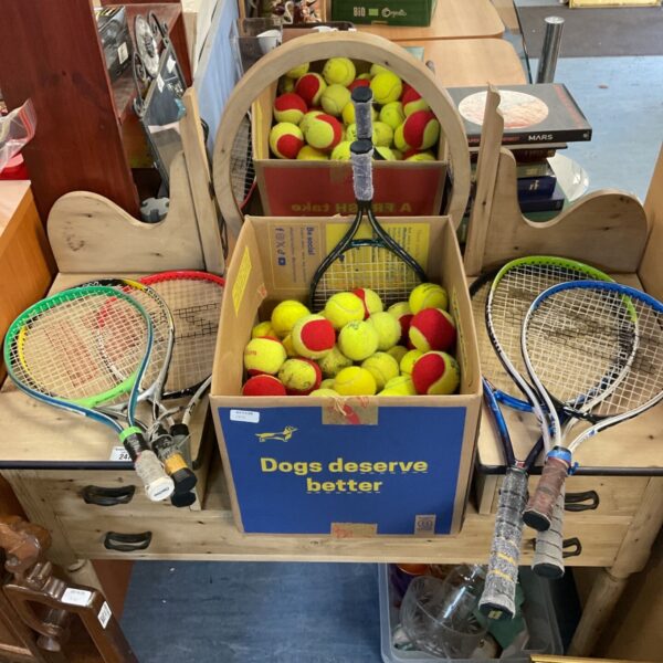 Selection of tennis rackets and boxes of tennis balls displayed on a pine stand