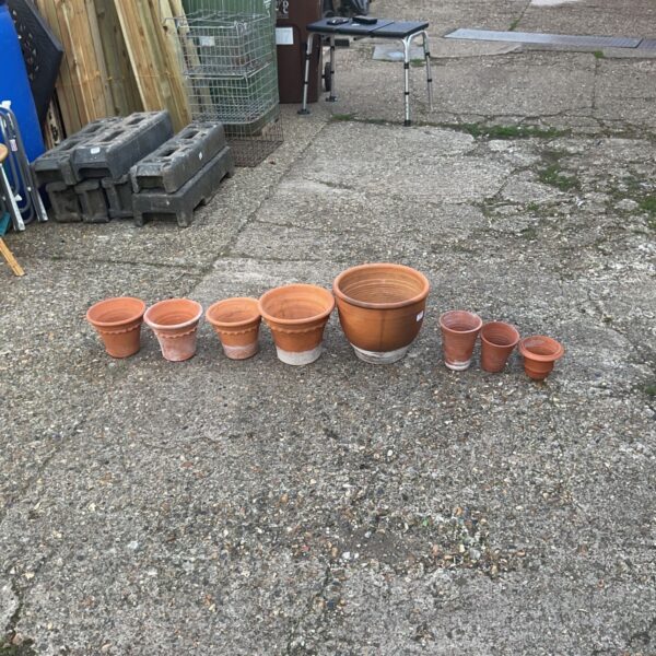 Assorted terracotta flower pots displayed outdoors in a garden setting.