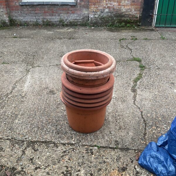 Stack of weathered terracotta flower pots for garden planting.