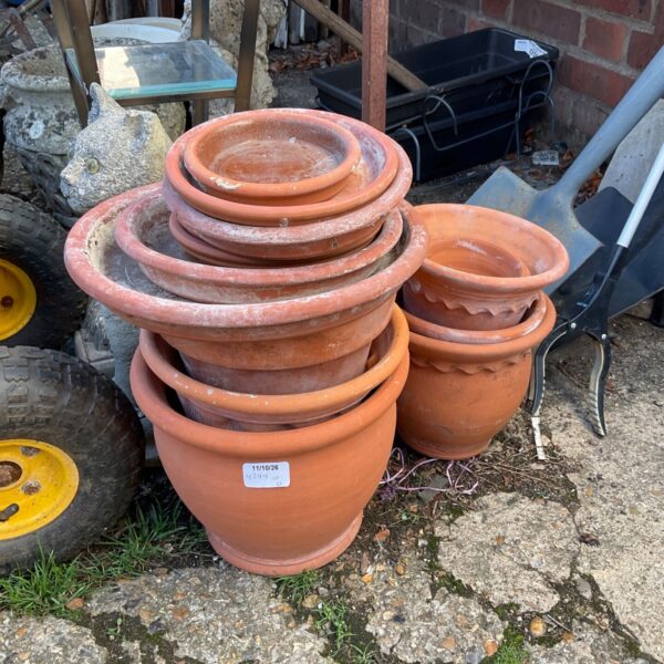 Stack of weathered terracotta flower pots in a garden setting.