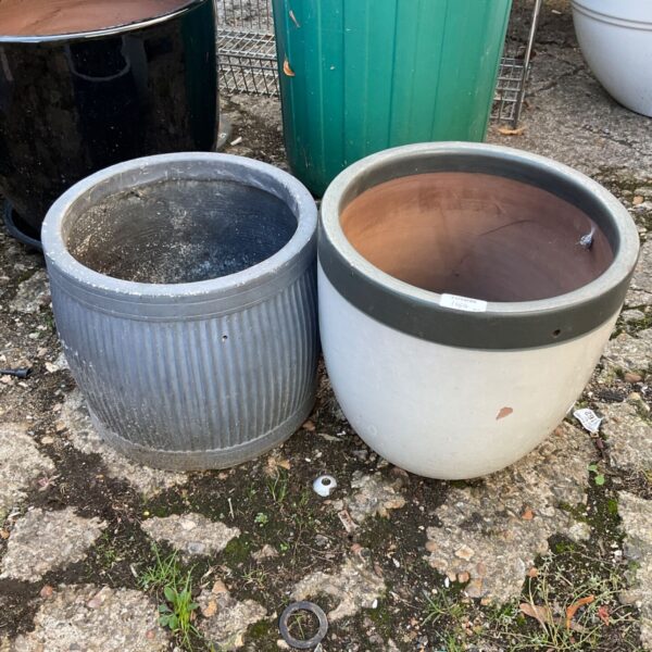 Two ribbed terracotta garden planters in a garden setting.