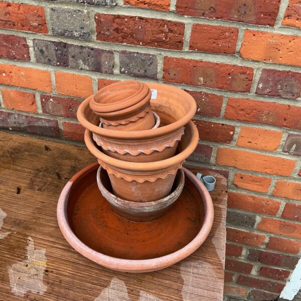 Stacked terracotta plant pots with scalloped rims and large saucer