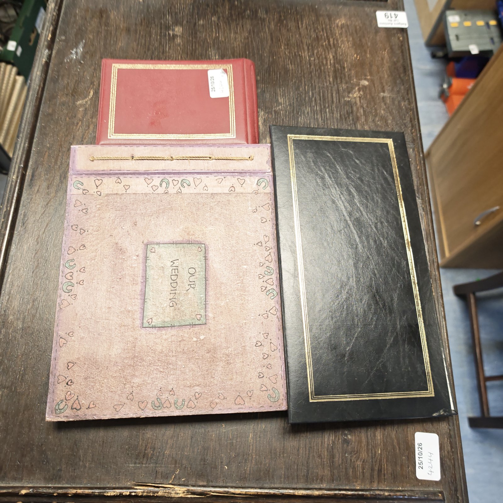 Three photo albums with red, pink decorated wedding and black gold-bordered covers