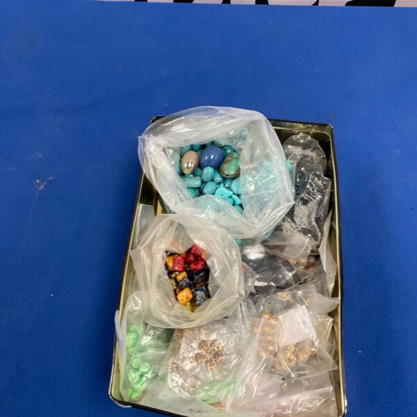 Metal tin containing bagged loose beads and jewellery components in turquoise, red and green