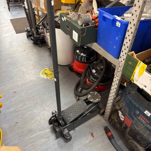 Used trolley jack with extension handle in a garage setting.