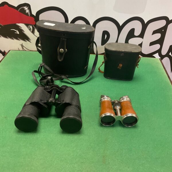 Two pairs of vintage binoculars and opera glasses with cases on green surface