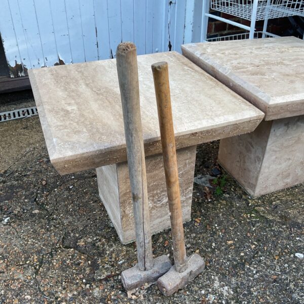 Two sledge hammers with wooden handles standing upright on a gravelled surface