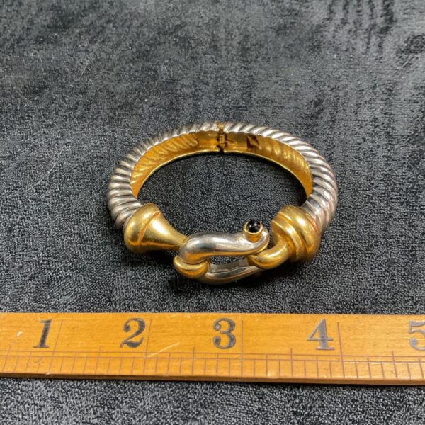 Close-up of two-tone twisted cable bracelet with shackle clasp.