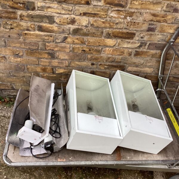 Two white ceiling light housings with silver reflector and spare lamp parts on trolley
