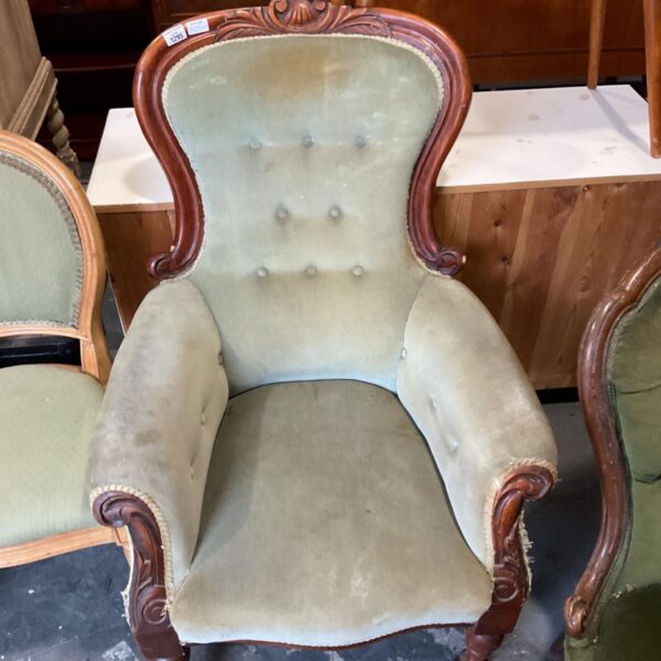 Victorian mahogany spoon-back armchair with green buttoned upholstery and carved arms