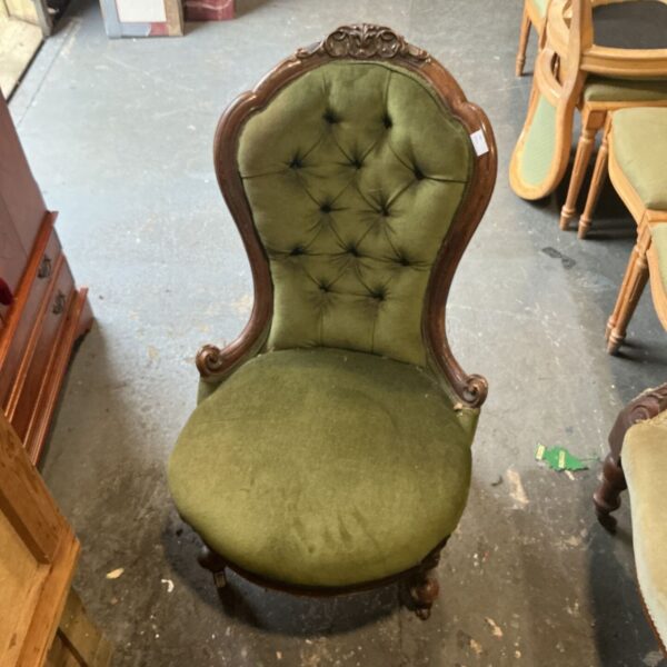 Antique Victorian nursing chair with green button-back upholstery and carved frame
