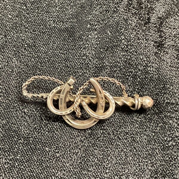 Victorian silver horseshoe and riding crop brooch with interlinked horseshoes and twisted crop