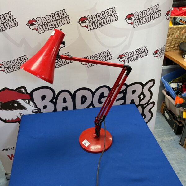 Red vintage Anglepoise Model 90 desk lamp on a dark surface.