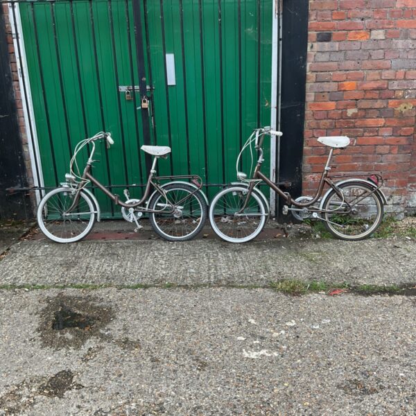 Pair of vintage Astraa children's bicycles leaning against a green door.