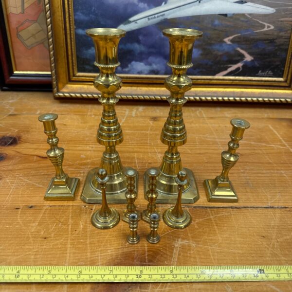 Group of vintage brass candlesticks on a patterned surface.
