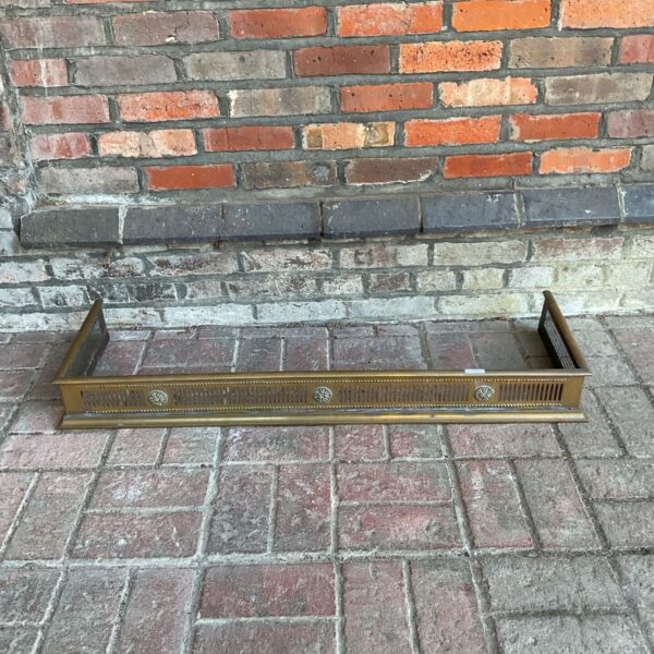 Vintage brass fireplace fender with rosette detailing.