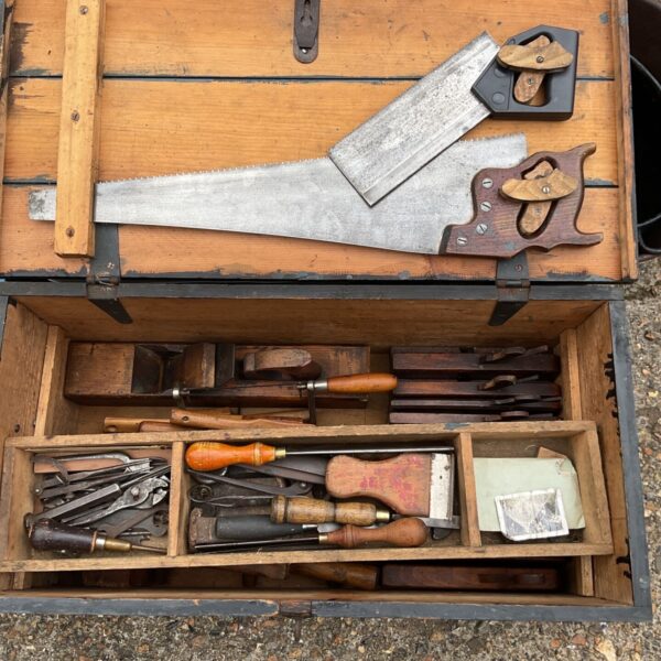 Open vintage carpenter's tool chest filled with antique tools.