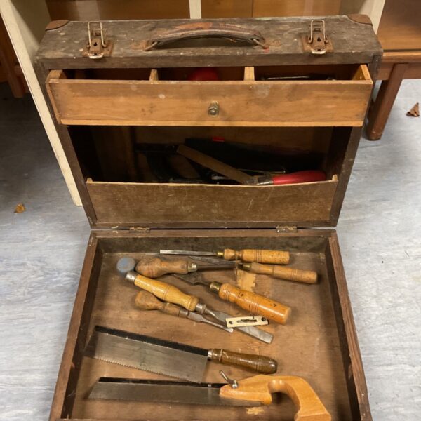 Wooden carpenter's tool chest open with chisels and saws