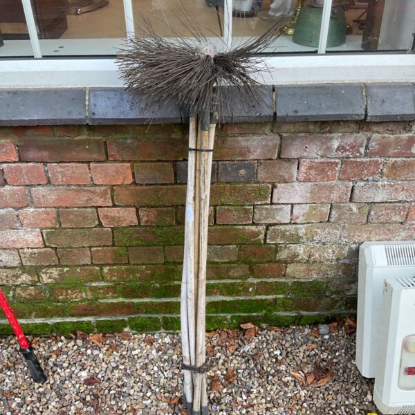 Vintage chimney sweep brush with wooden poles and bristles.