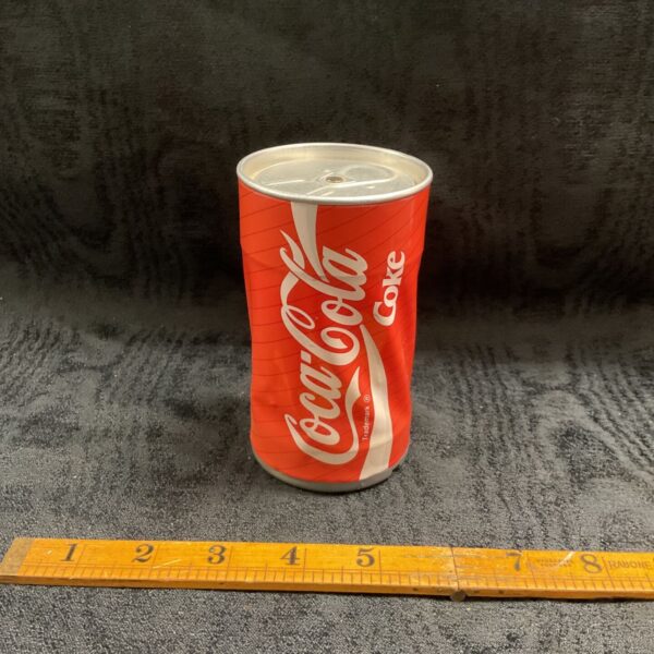Vintage crushed red Coca-Cola dancing can with white script logo on dark background