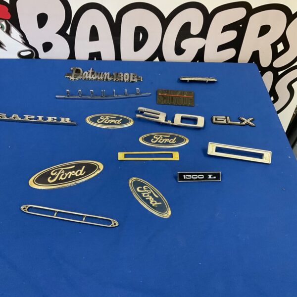 Vintage Datsun car badges collection, including a 1200 emblem.