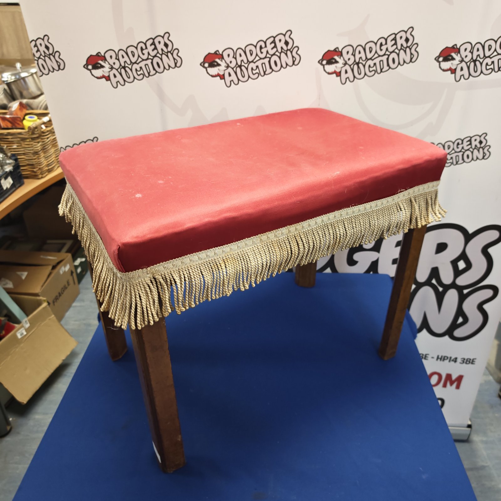 Vintage red upholstered dressing table stool with wooden legs.