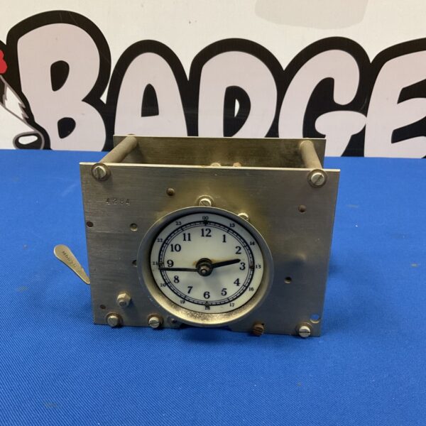 Vintage factory clock movement with white dial and brass casing.
