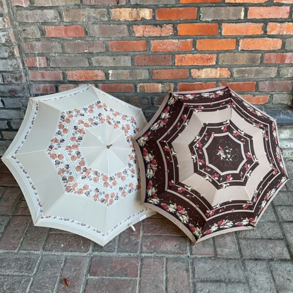 Two vintage floral umbrellas against a brick wall.