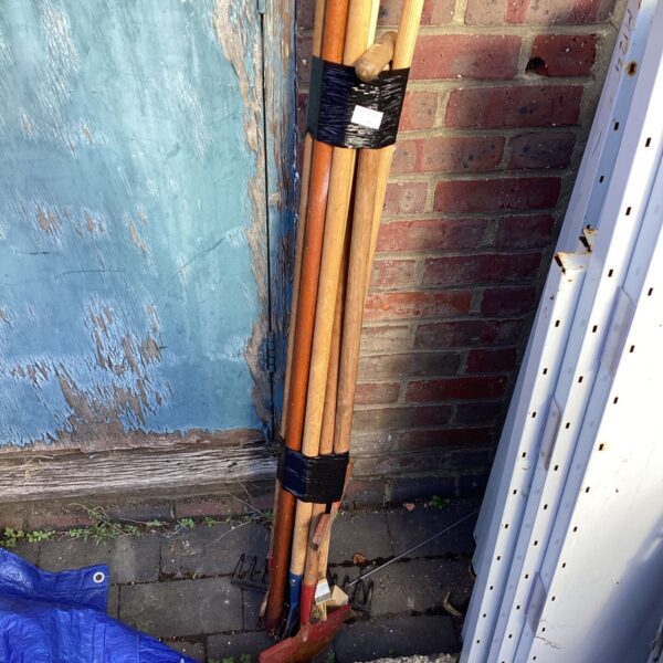 Vintage garden tool set leaning against a blue door.