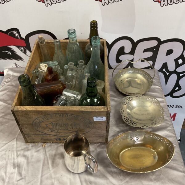 Vintage glass bottles and silver plate items in a wooden crate
