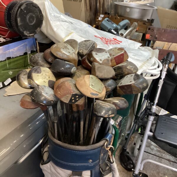 Large quantity of vintage wooden-headed golf clubs in a blue golf bag