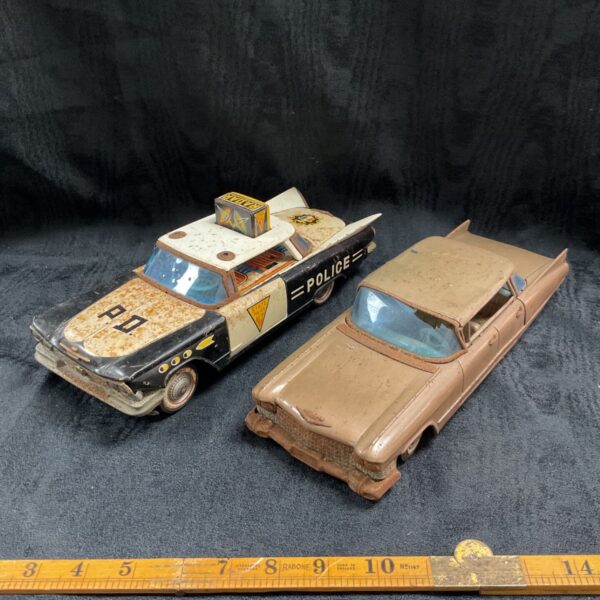 Vintage Japanese tinplate police car and Cadillac toy car lot.
