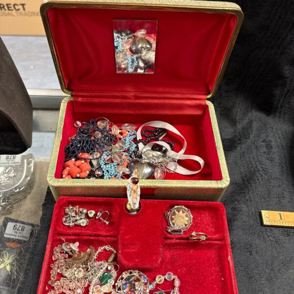 Vintage musical jewellery box open with red velvet lining and mixed costume jewellery