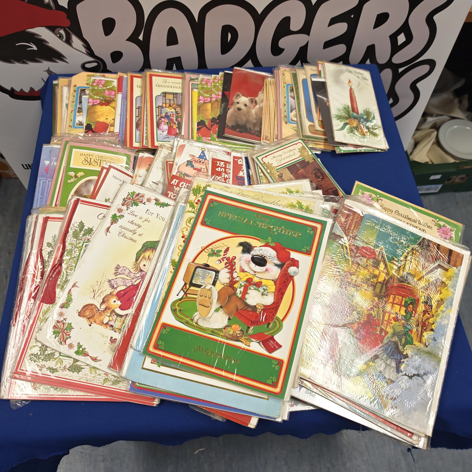Assorted vintage and novelty Christmas cards spread across a blue table