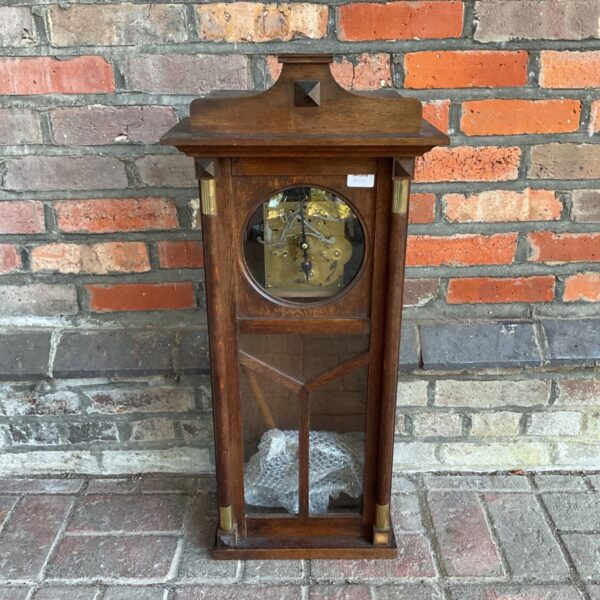 Vintage oak wall clock with exposed movement and pendulum.