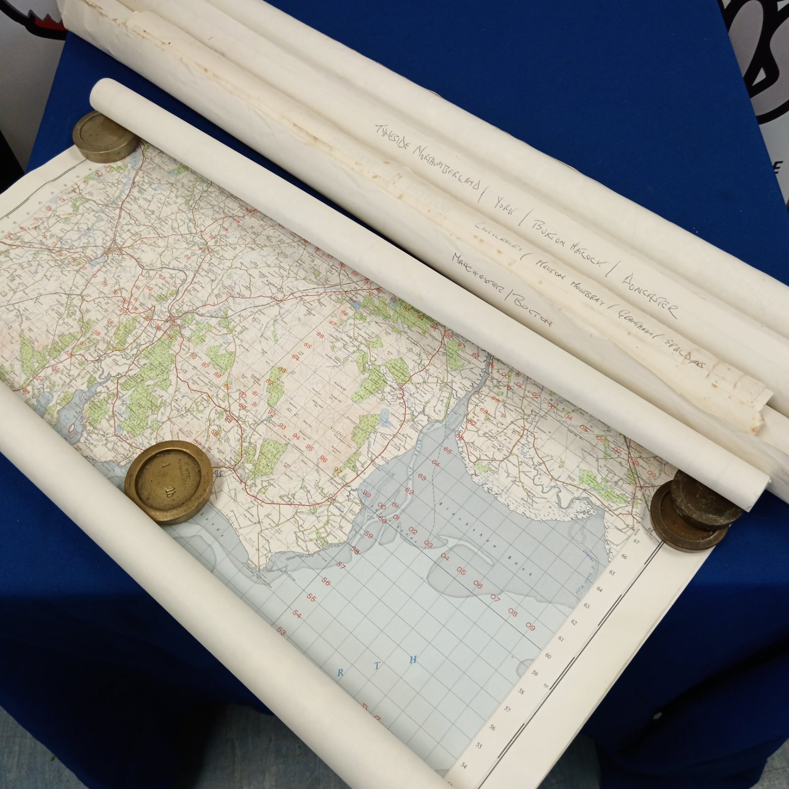 Vintage Ordnance Survey maps rolled and tied with ribbon.