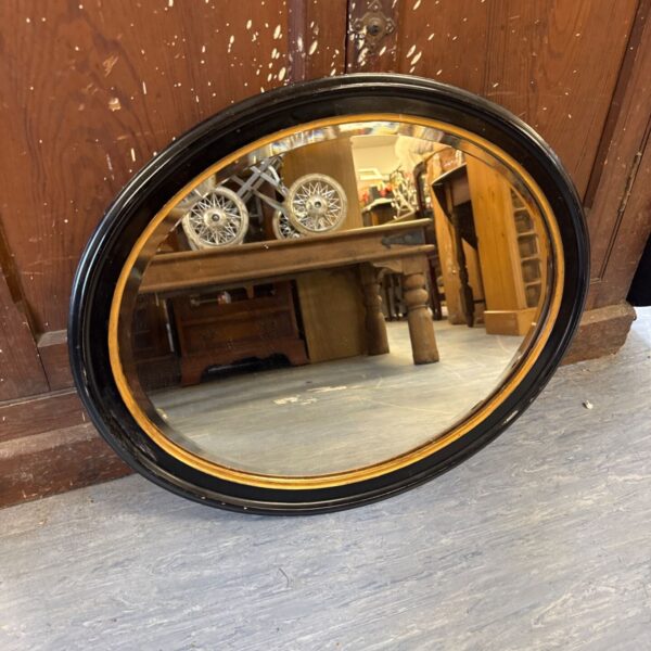 Vintage oval mirror with bevelled glass for wall decoration.