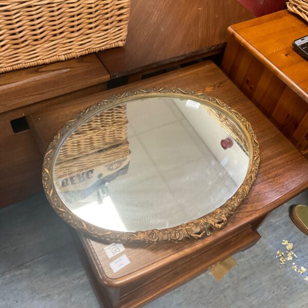 Vintage oval framed mirror with ornate gold-toned scroll and floral border