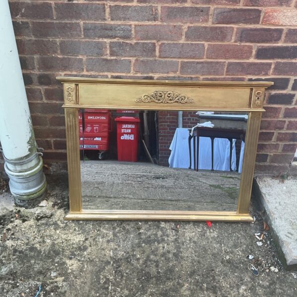 Vintage giltwood overmantel mirror displayed outdoors.