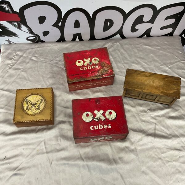 Two red vintage Oxo cubes tins and two wooden storage boxes on grey fabric