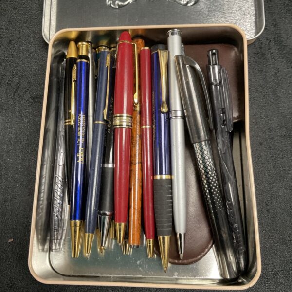 Assorted vintage pens in a decorative tin, collectible writing instruments.