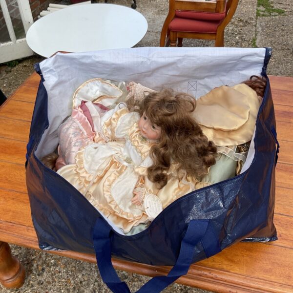Blue bag filled with a lot of vintage porcelain dolls.