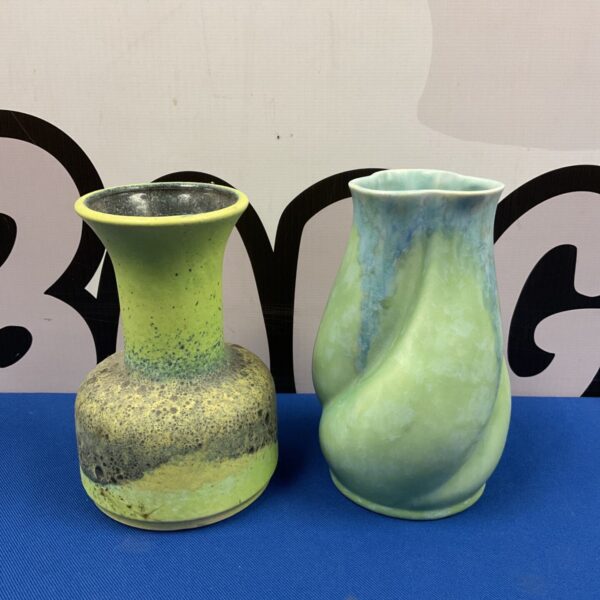 Vintage green pottery vase with speckled glaze on blue background.