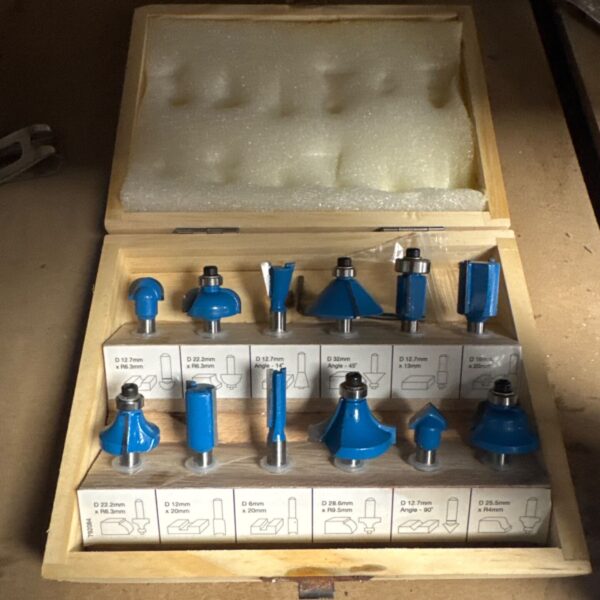 Vintage router bit set in wooden case for woodworking projects.