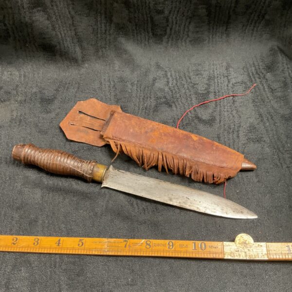 Vintage sheath knife with a worn leather sheath.