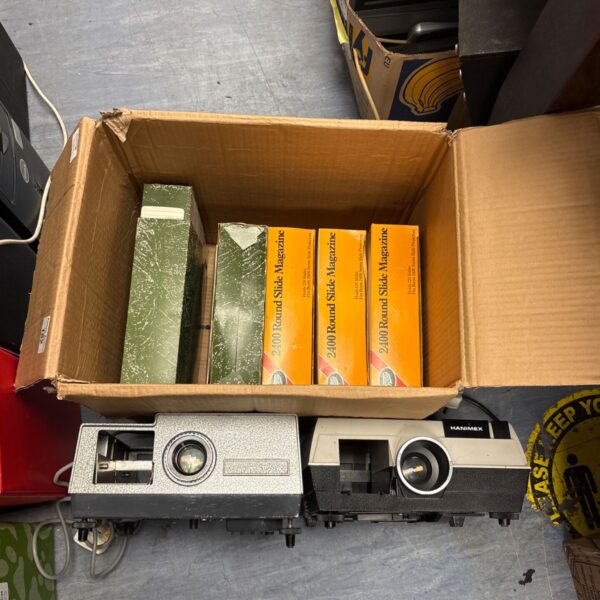 Two vintage slide projectors and round slide magazines in cardboard box