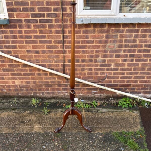 Vintage wooden standard lamp against brick wall.